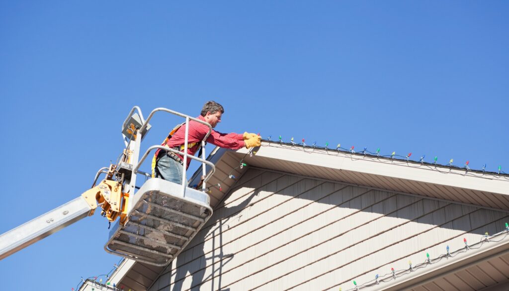 Professional installer hanging LED Christmas lights on a roof of a house in Portland, Oregon, during the holiday season